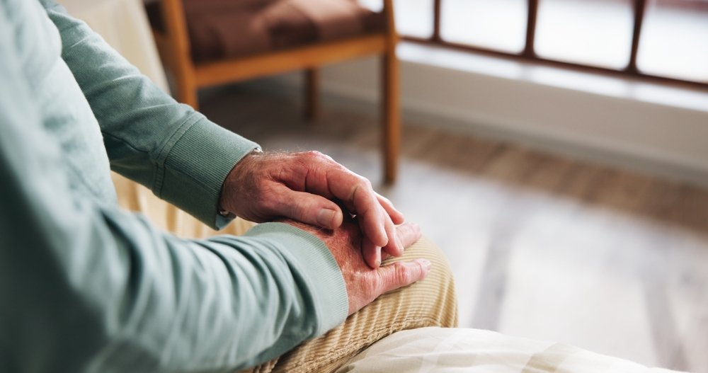Senior sitting with hands folded, thinking.