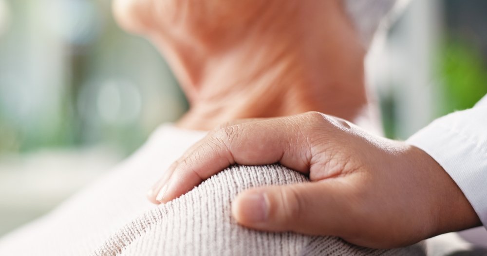 A hand on an elderly person’s shoulder.